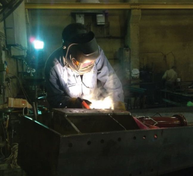 Welder fabricating a steel component in the factory